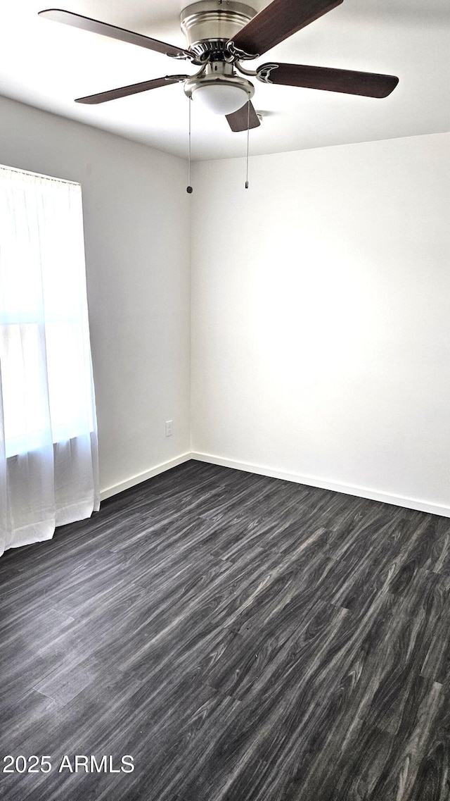spare room with a ceiling fan, baseboards, and dark wood-style floors