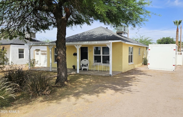 view of front of property featuring concrete block siding, a shingled roof, and fence