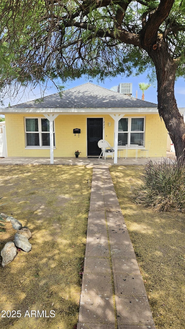 view of front of property with concrete block siding, a shingled roof, and a porch