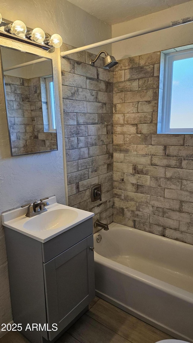 bathroom with wood finished floors, vanity, shower / washtub combination, and a textured wall