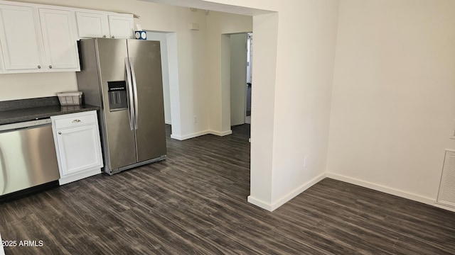 kitchen with appliances with stainless steel finishes, dark countertops, dark wood-style floors, and baseboards