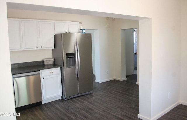 kitchen with appliances with stainless steel finishes, dark countertops, baseboards, white cabinets, and dark wood-style flooring