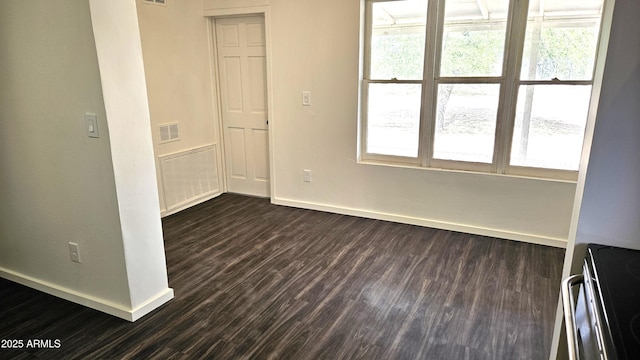 empty room featuring baseboards, dark wood finished floors, and healthy amount of natural light