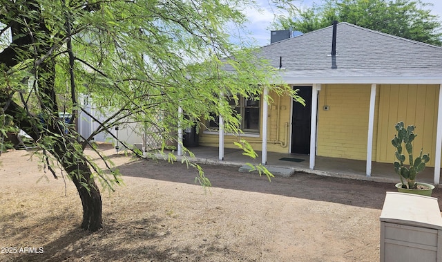 view of front of home with a shingled roof, brick siding, covered porch, and a chimney