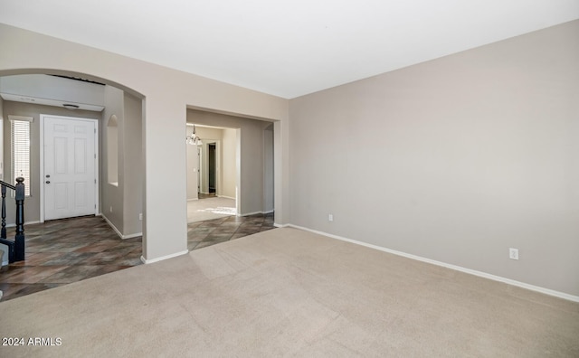 carpeted empty room with an inviting chandelier