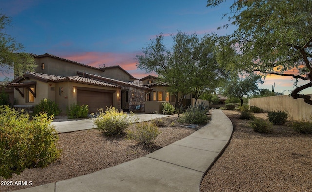 mediterranean / spanish house with stucco siding, a garage, a tile roof, and driveway