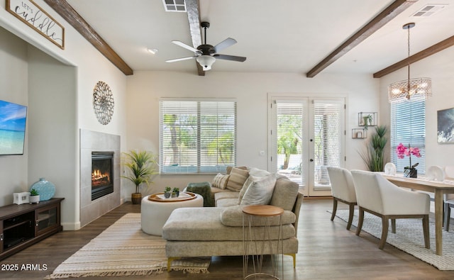 living room with beam ceiling, dark wood-style flooring, healthy amount of natural light, ceiling fan, and a tiled fireplace