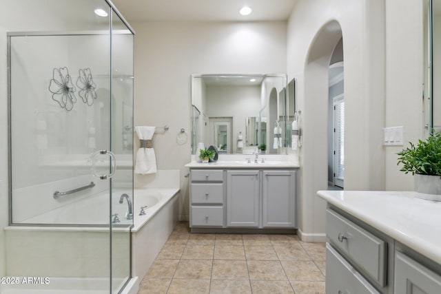 full bathroom featuring a shower stall, two vanities, a garden tub, tile patterned floors, and recessed lighting