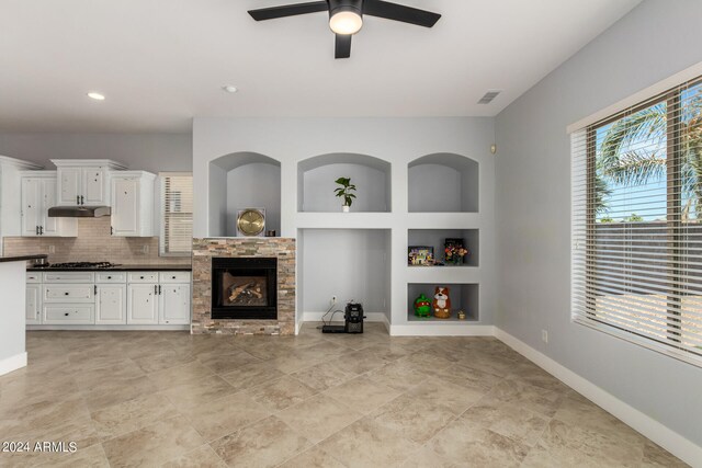 unfurnished living room featuring built in features, a fireplace, light tile patterned floors, and ceiling fan