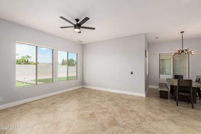 spare room featuring light tile patterned floors and ceiling fan with notable chandelier