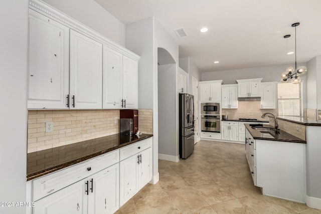 kitchen featuring decorative backsplash, appliances with stainless steel finishes, white cabinets, pendant lighting, and sink