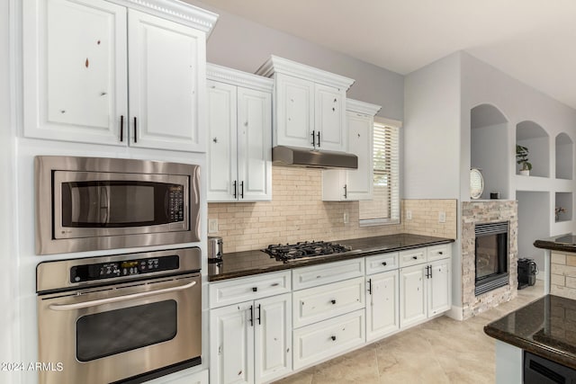 kitchen featuring white cabinetry, appliances with stainless steel finishes, dark stone countertops, light tile patterned flooring, and tasteful backsplash