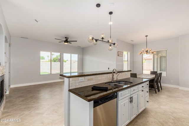 kitchen featuring tasteful backsplash, ceiling fan with notable chandelier, stainless steel dishwasher, white cabinets, and sink