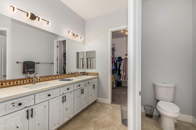 bathroom with double sink vanity, toilet, and tile patterned flooring