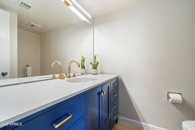 bathroom featuring visible vents, toilet, vanity, and baseboards