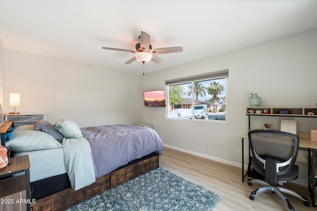 bedroom featuring a ceiling fan, baseboards, and wood finished floors