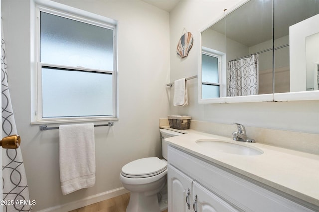 bathroom with toilet, vanity, baseboards, and wood finished floors