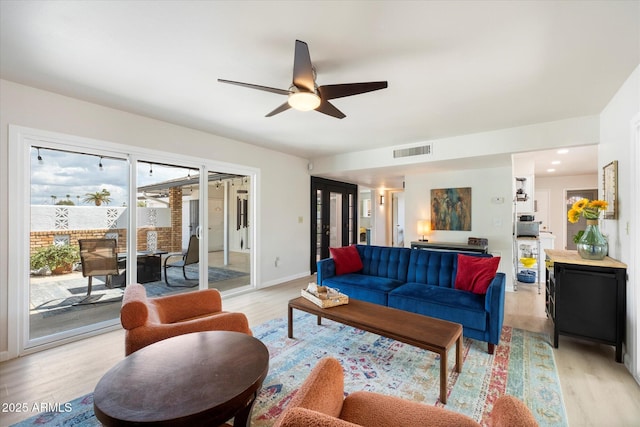 living area with ceiling fan, baseboards, visible vents, and light wood-type flooring