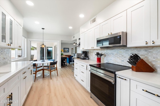 kitchen featuring light wood finished floors, visible vents, glass insert cabinets, stainless steel appliances, and white cabinetry