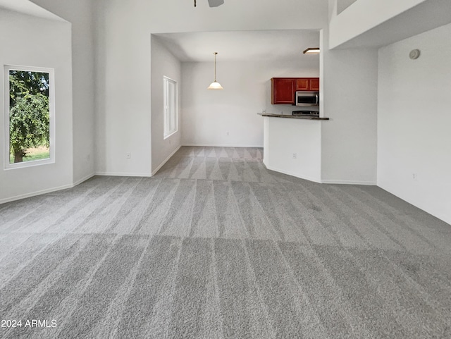 empty room with ceiling fan, carpet floors, and a high ceiling