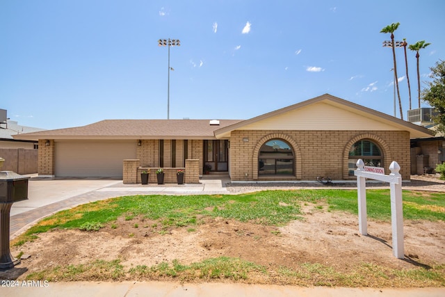 ranch-style home featuring an attached garage, driveway, central AC unit, and brick siding