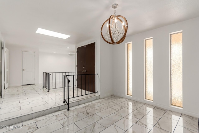 unfurnished room featuring a skylight, marble finish floor, recessed lighting, a chandelier, and baseboards