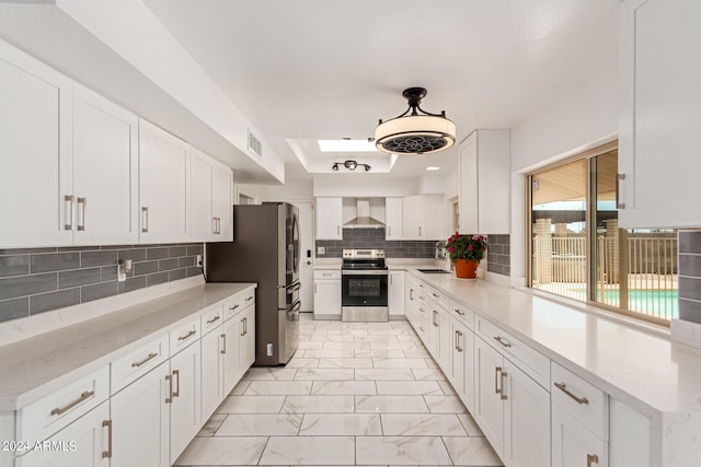 kitchen featuring stainless steel appliances, white cabinetry, marble finish floor, wall chimney range hood, and light countertops