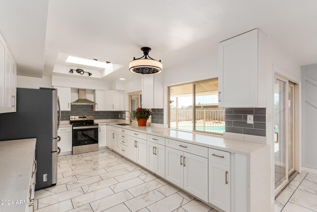 kitchen featuring marble finish floor, stainless steel appliances, white cabinetry, a sink, and wall chimney exhaust hood