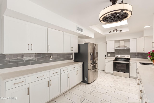 kitchen featuring visible vents, wall chimney exhaust hood, appliances with stainless steel finishes, marble finish floor, and white cabinetry