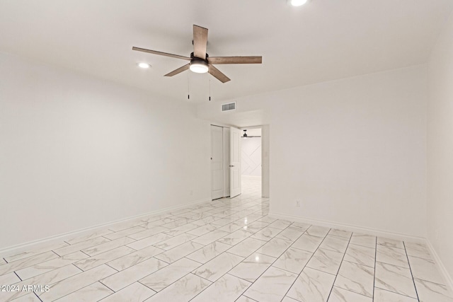 empty room with marble finish floor, visible vents, ceiling fan, and baseboards