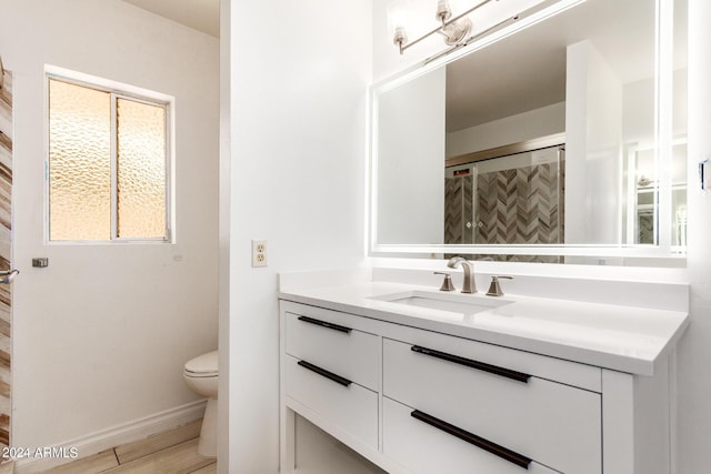 bathroom featuring baseboards, toilet, wood finished floors, an enclosed shower, and vanity