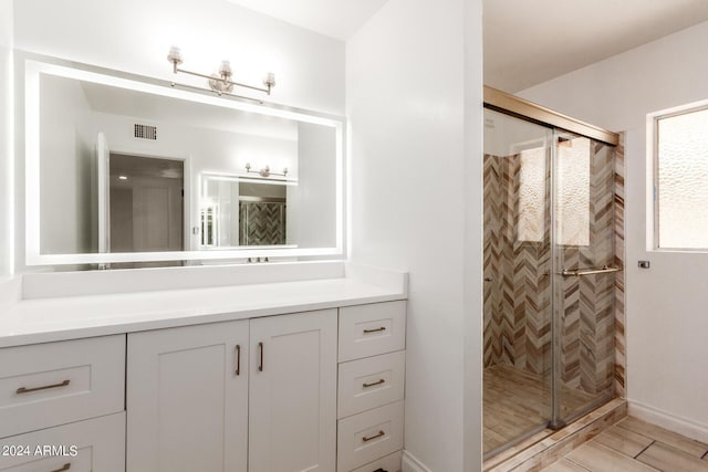 bathroom with a stall shower, vanity, and visible vents