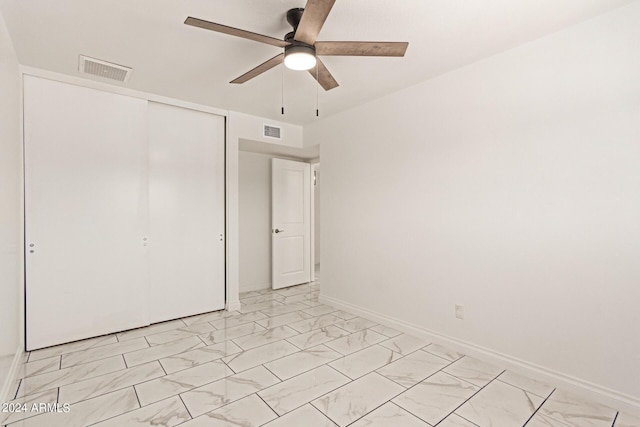 unfurnished bedroom with marble finish floor, a closet, and visible vents