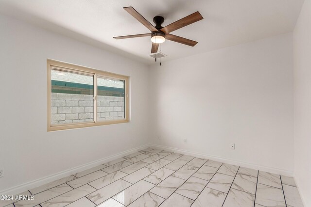 spare room with marble finish floor, ceiling fan, visible vents, and baseboards