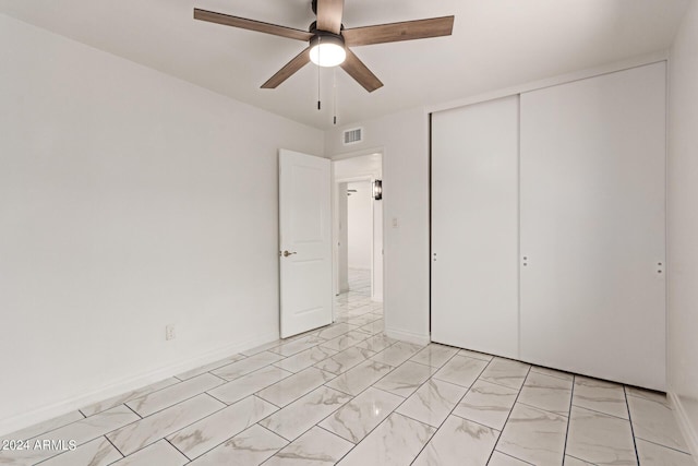 unfurnished bedroom featuring marble finish floor, a closet, visible vents, ceiling fan, and baseboards