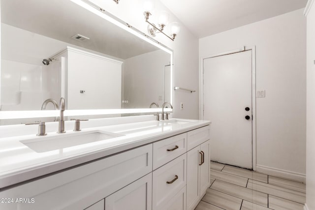 bathroom with double vanity, visible vents, and a sink