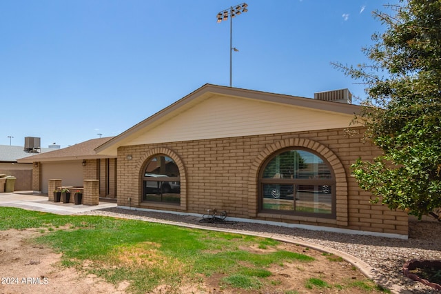 entrance to property featuring a garage, a patio, central AC, and brick siding