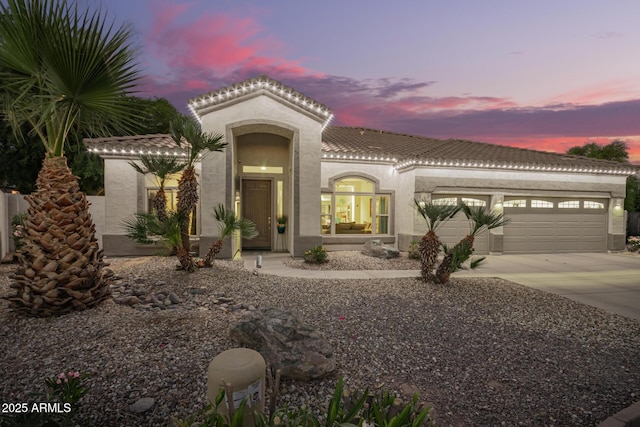 mediterranean / spanish-style house featuring a tiled roof, stucco siding, concrete driveway, and a garage