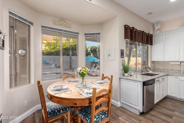 kitchen featuring a sink, stainless steel dishwasher, white cabinetry, and wood finished floors