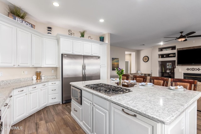 kitchen featuring a kitchen island, a ceiling fan, appliances with stainless steel finishes, dark wood finished floors, and open floor plan