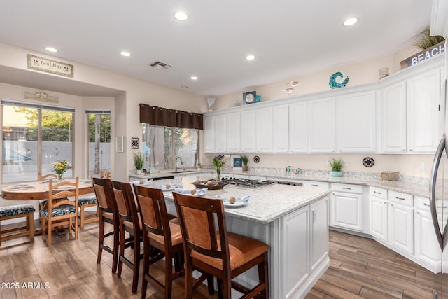 kitchen with light wood-style flooring, a center island, white cabinetry, recessed lighting, and visible vents