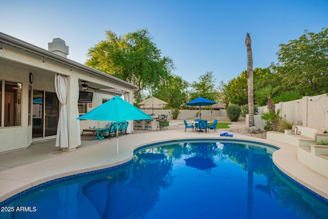 view of swimming pool featuring a ceiling fan, a fenced in pool, a fenced backyard, a patio, and outdoor dining space
