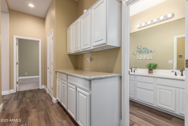 hall featuring recessed lighting, baseboards, dark wood-style floors, and a sink