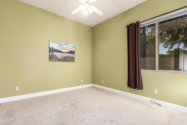carpeted spare room with a ceiling fan and baseboards