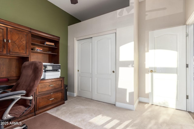 office space featuring a ceiling fan, baseboards, and light carpet