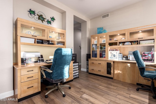 home office featuring built in study area, baseboards, wood finished floors, and visible vents