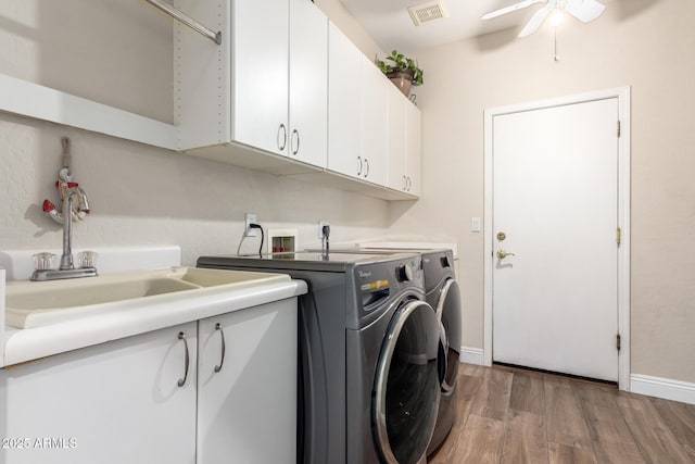 clothes washing area featuring cabinet space, light wood-style floors, separate washer and dryer, a ceiling fan, and visible vents