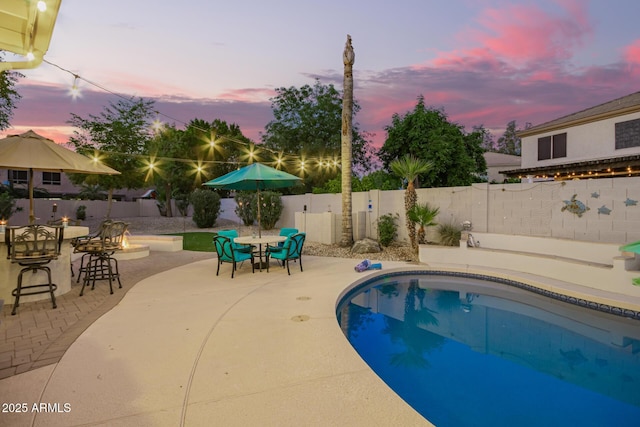 pool at dusk with a patio, a fenced in pool, outdoor dining area, and a fenced backyard