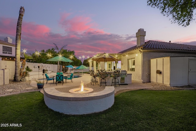 exterior space featuring fence, a fire pit, a patio area, and outdoor dry bar