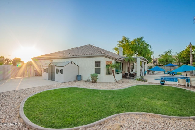 back of property at dusk with a yard, a fenced in pool, a fenced backyard, and a patio area